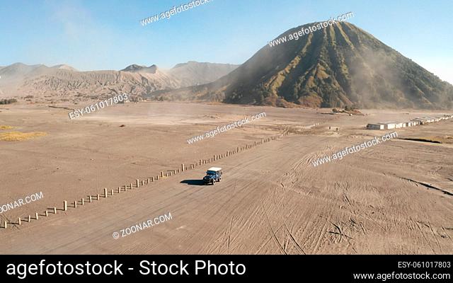 Cinematic shot aerial drone view of tour jeep cruise at beautiful Mount Bromo volcano with desert in East Java, Indonesia