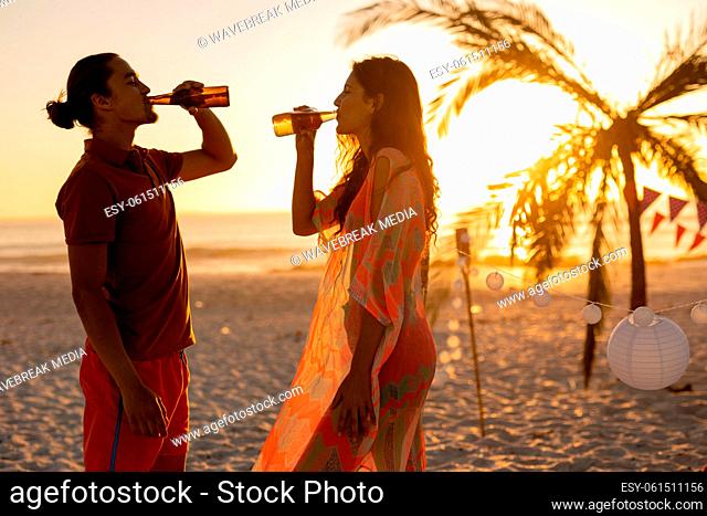 Caucasian couple drinking alcohol on beach