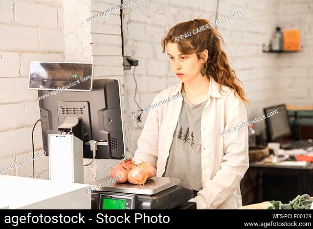 Grocer weighing onions on weight scale in shop