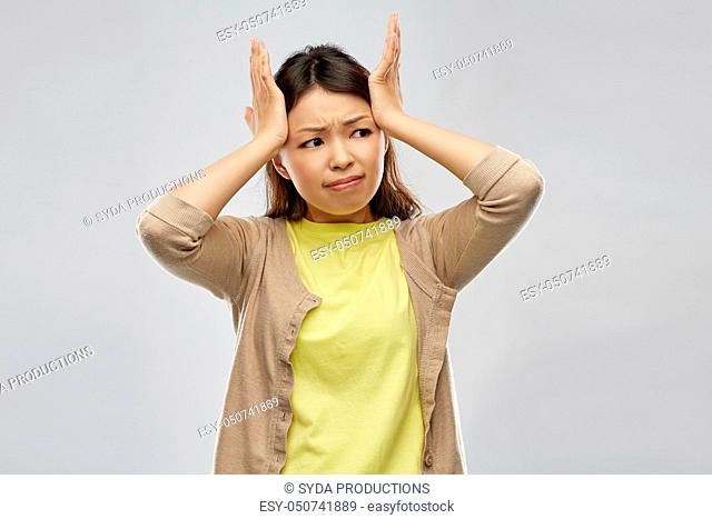 stressed asian woman holding to her head