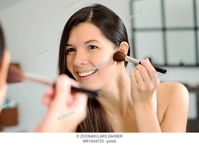 Attractiv happy woman applying makeup
