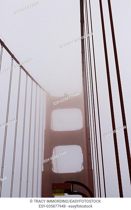 The top half of the tower and cables of the Golden Gate Bridge shrouded in fog, San Francisco, California, USA