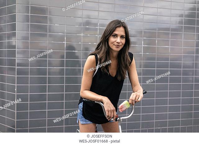 Smiling woman with ice lolly and bicycle