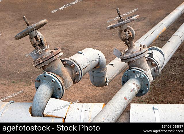 Old made of steel hot water pipes with two valves outdoors