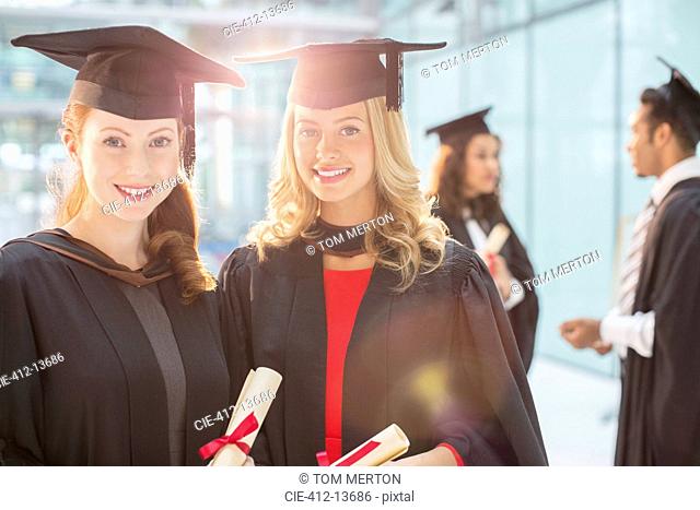 Smiling graduates holding diplomas