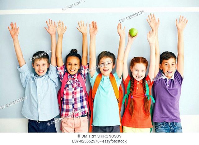 Row of ecstatic schoolmates with raised arms looking at camera
