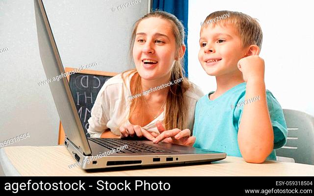 Happy smiling mother with little son using laptop and looking on computer screen