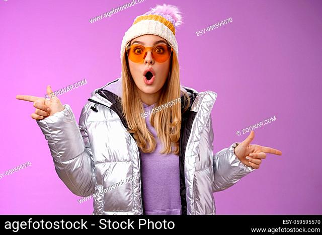 Lifestyle. Impressed blond girl gasping widen eyes surprised folding lips wow sound check out incredible discounts winter equipment pointing left right cannot...