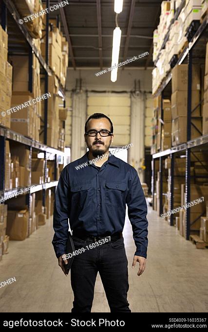 Young hispanic warehouse worker smiling and looking straight into camera