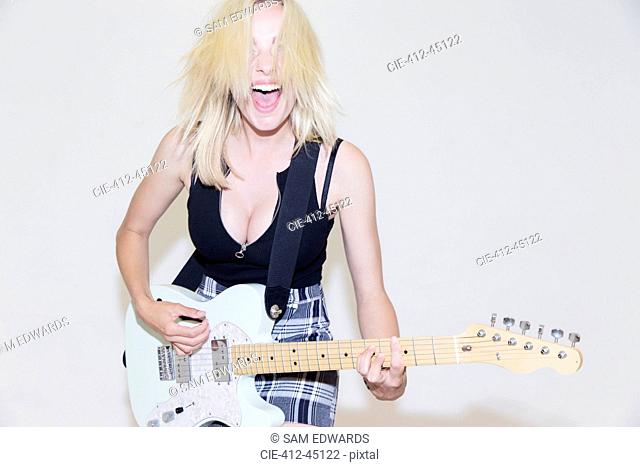 Portrait exuberant young woman playing electric guitar