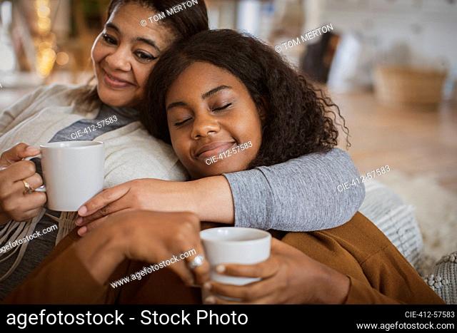 Cariñosa madre e hija abrazados con té