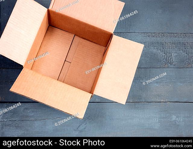Empty open cardboard box for postal items on a wooden background. Top view, copy space