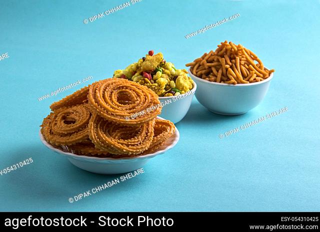 Indian Snack : Chakli, chakali or Murukku and Besan (Gram flour) Sev and chivada or chiwada on blue background. Diwali Food