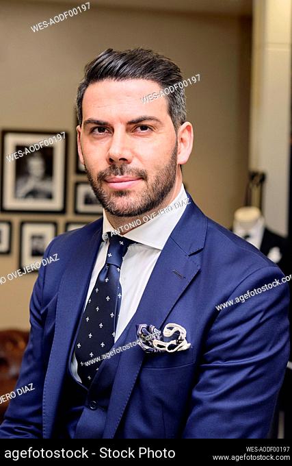 Portrait of man in dark blue suit in tailors boutique