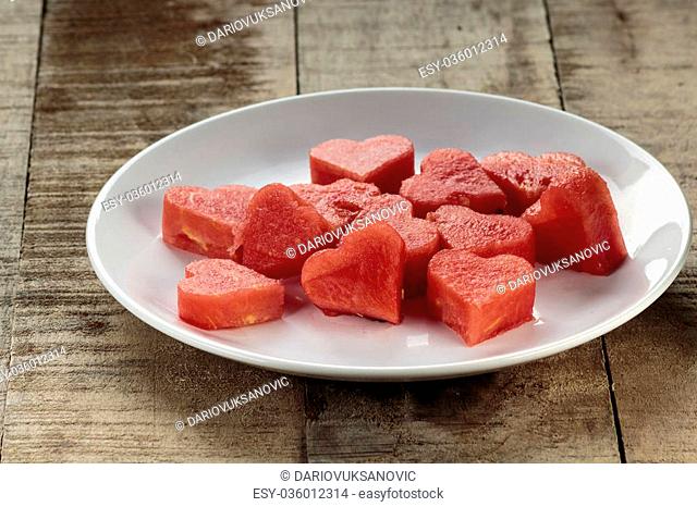 Slices of watermelon in the heart shape on vintage wooden table