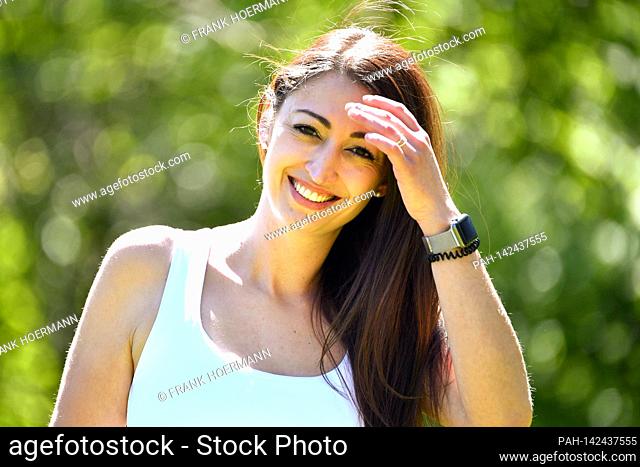 Pretty long-haired young woman (30 years old) in a white top looks smiling at the camera. Model released! | usage worldwide