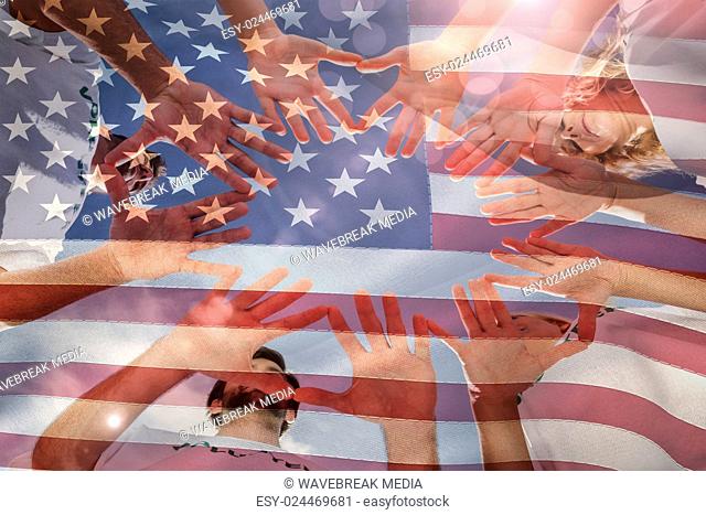 Composite image of volunteers with hands together against blue sky