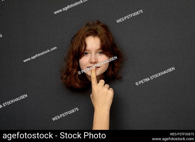 Studio shot of head of teenage girl shushed by male hand