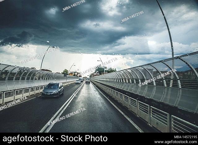 Italy, Veneto, Belluno. View on the road from inside a car, with dramatic sky and oncoming thunderstorm