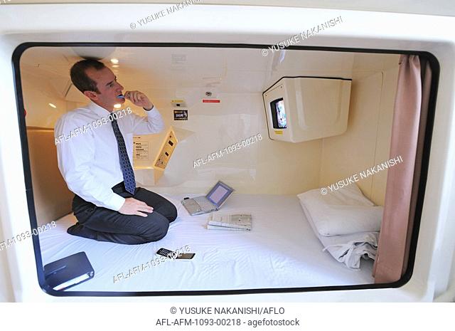 Businessman brushing in chamber of capsule hotel
