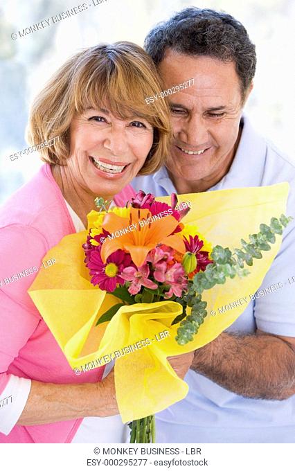 Husband and wife holding flowers and smiling