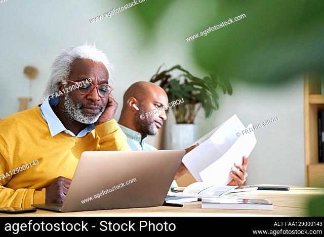 Father and son using laptop and reading documents