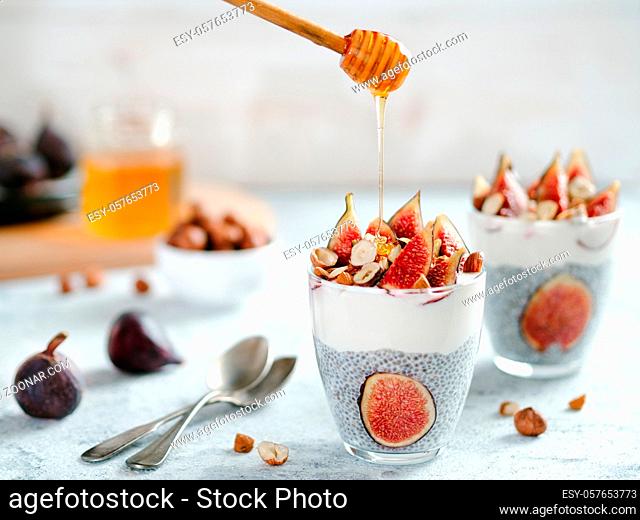 Healthy chia pudding with yogurt, figs and nuts in glass. Ideas and recipes for healthy breakfast, snack or dessert. Honey drips into glass with chia seeds...