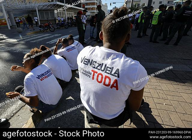 03 December 2023, Venezuela, Caracas: A group of people wearing T-shirts with the slogan ""All of Venezuela, El Esequibo is ours"" stand outside a polling...