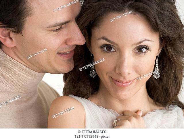 Man whispering in woman's ear