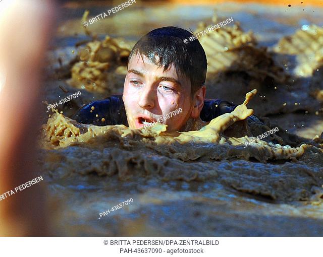 A participant swims through a mud hole during the Cross Challenge 2013 race in Doeberitz, Germany, 27 October 2013. Around 1