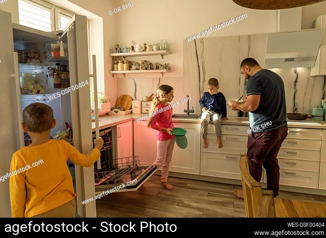 Girl and boys with father in kitchen at home