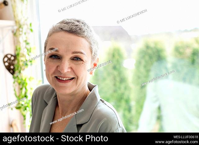 Portrait of mature woman with short grey hair at the window