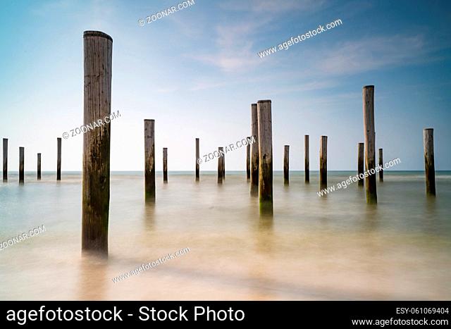 Long exposure seascape. Taken at the North Sea in Petten with the pole village in the sea, Blue sky, sun and shodows. Focus on foreground