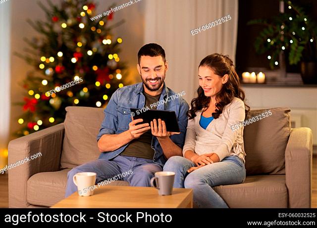 happy couple using tablet pc at home on christmas