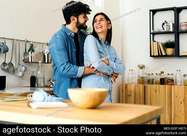 Cheerful couple embracing each other in kitchen at home