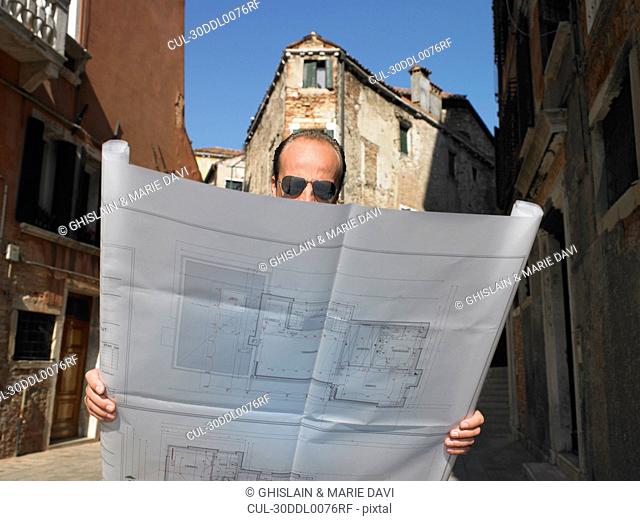 Man looking at blue prints in the street