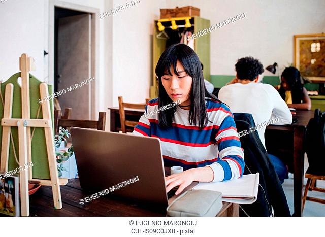 Young businesswoman remote working on laptop at cafe table