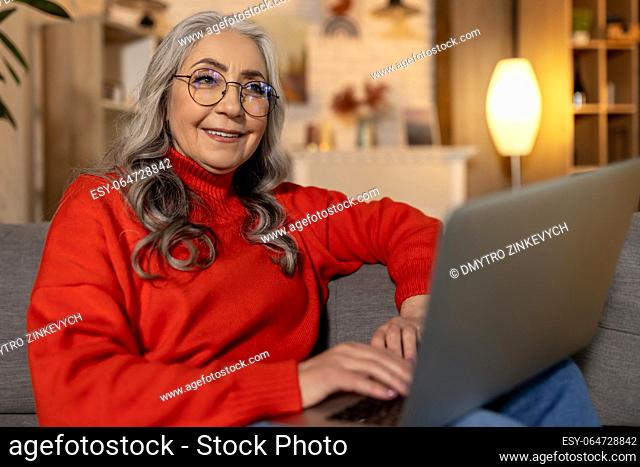 Woman at home. Woman in red shirt watching something on laptop