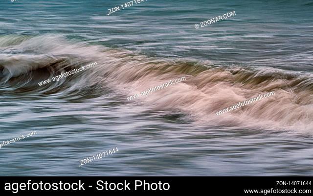An abstract, long-exposure image of a wave breaking on the beach