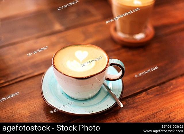 From above of ceramic cups on saucers with freshly brewed latte with hearts on froth
