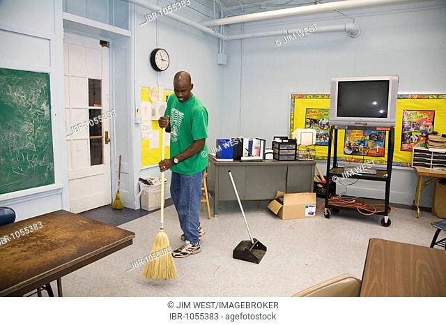Daren Stacker, a custodian at New Orleans Charter Science and Math High School, sweeping a classroom, New Orleans, Louisiana, USA