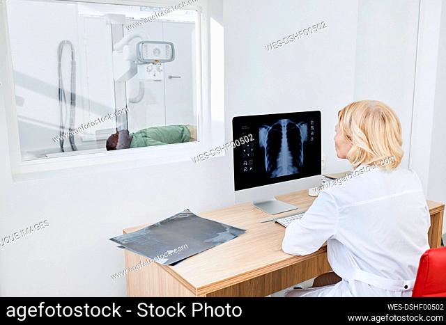 Radiologist taking X-ray shot of patient in clinic