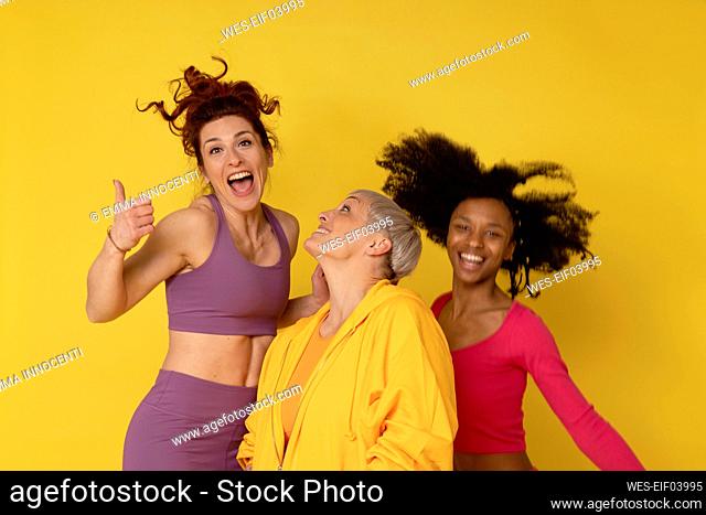 Multiracial friends having fun against yellow background