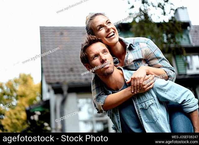 Man giving piggyback ride to happy girlfriend at backyard
