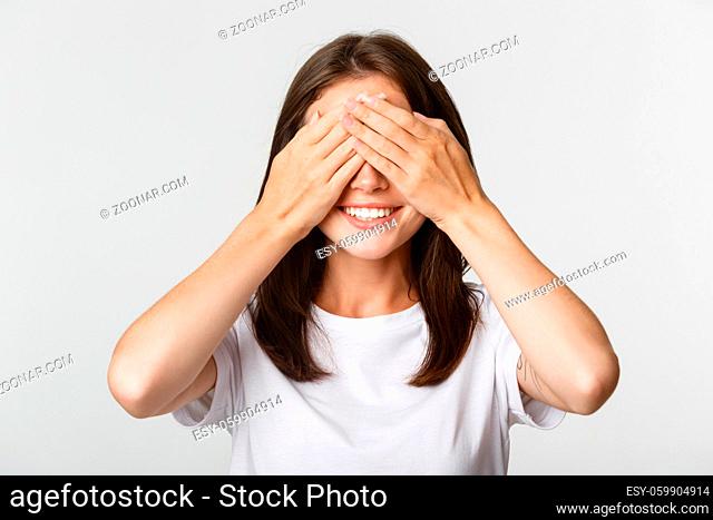 Portrait of smiling excited brunette girl close eyes and waiting for surprise