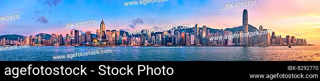 Panorama of Hong Kong skyline cityscape downtown skyscrapers over Victoria Harbour in the evening with junk tourist ferry boat on sunset with dramatic sky