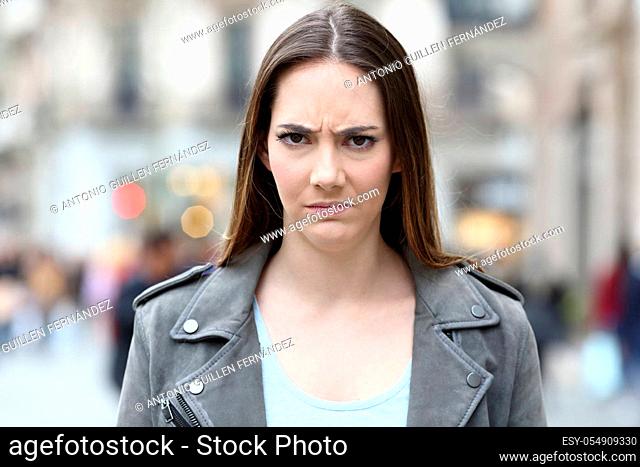 Front view portrait of an angry woman looking annoyed at camera on city street