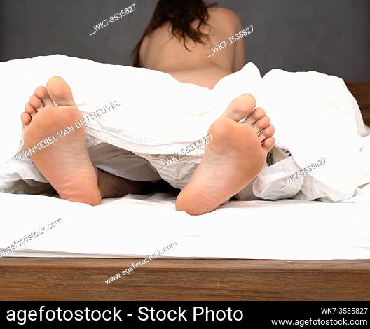 Couple in bed having sex with pair feet under the white sheets, valentines romantic concept love