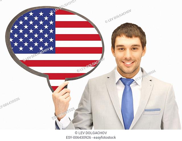 education, foreign language, english, people and communication concept - smiling young man or businessman in tie and suit holding text bubble of american flag