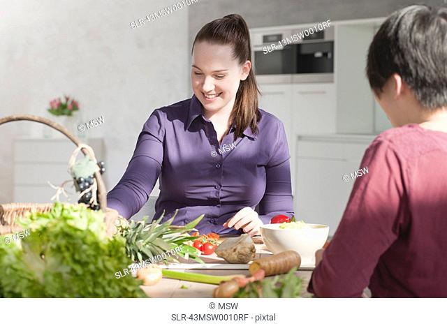 Women eating vegetables in kitchen